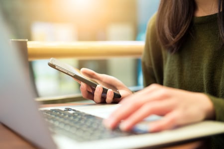 Woman connecting cellphone and laptop computer