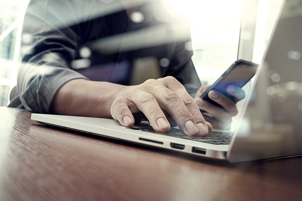 designer hand working and smart phone and laptop on wooden desk in office with london city background designer hand working and smart phone and laptop on wooden desk in office with london city background