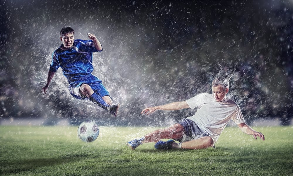 two football players in jump to strike the ball at the stadium-2
