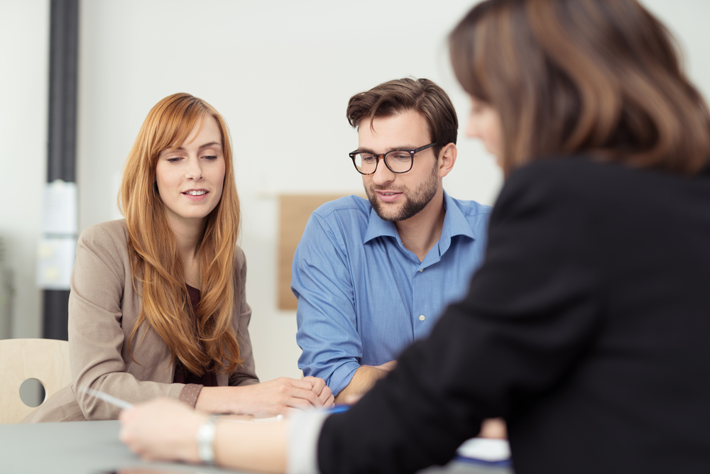 Broker making a presentation to a young couple showing them a document which they are viewing with serious expressions-Nov-10-2023-05-37-09-9041-AM