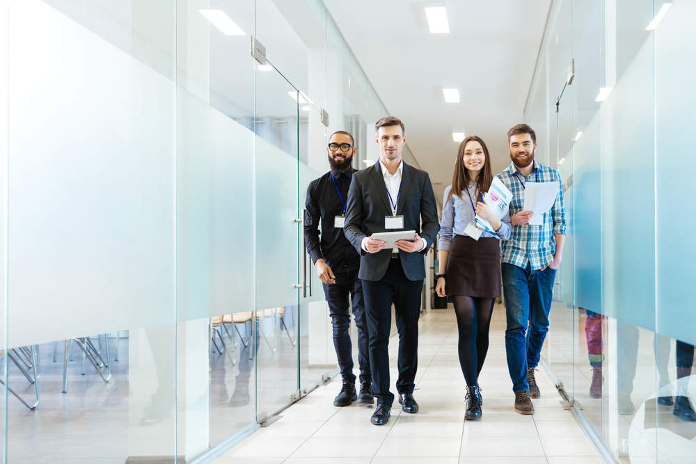 Full length of group of happy young business people walking the corridor in office together-2