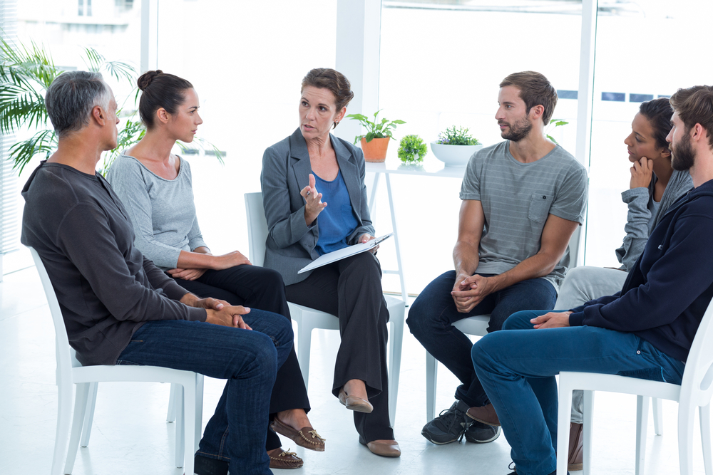 Group therapy in session sitting in a circle in a bright room-3