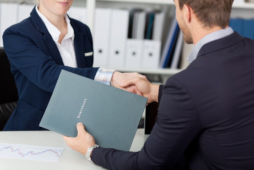 Midsection of a businessman shaking hands with a female interviewer in office-1