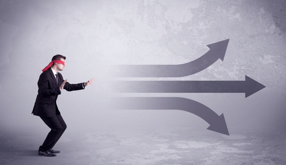 An amateur young sales person lost in a new situation concept with blindfolded businessman surrounded by drawn question marks.