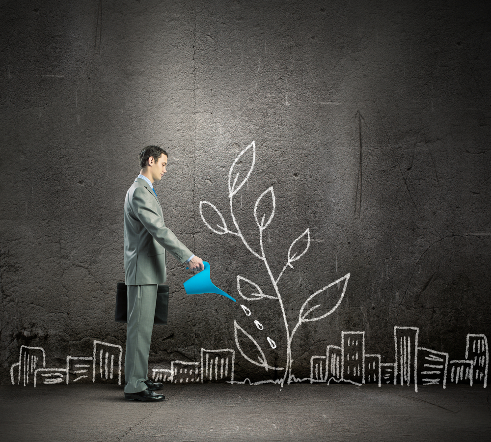 Image of businessman watering sprout with can