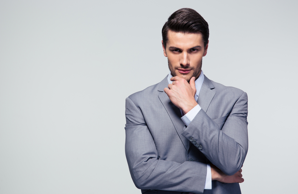 Portrait of a pensive businessman touching his chin over gray background-1