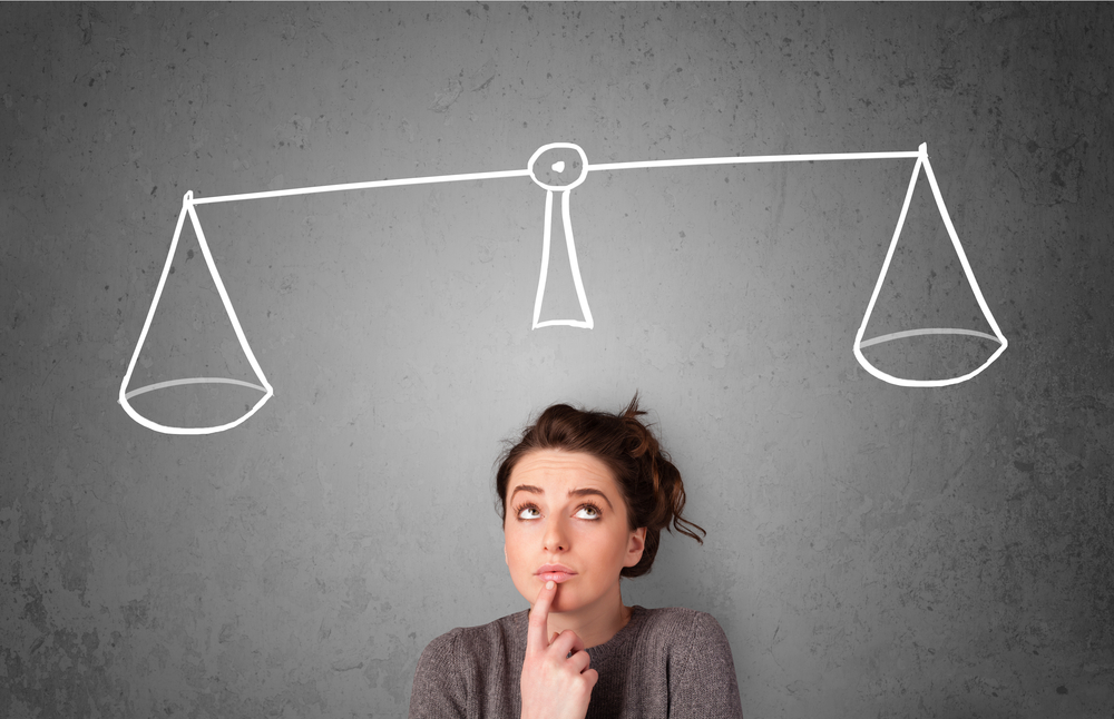 Pretty young lady taking a decision with scale above her head-2