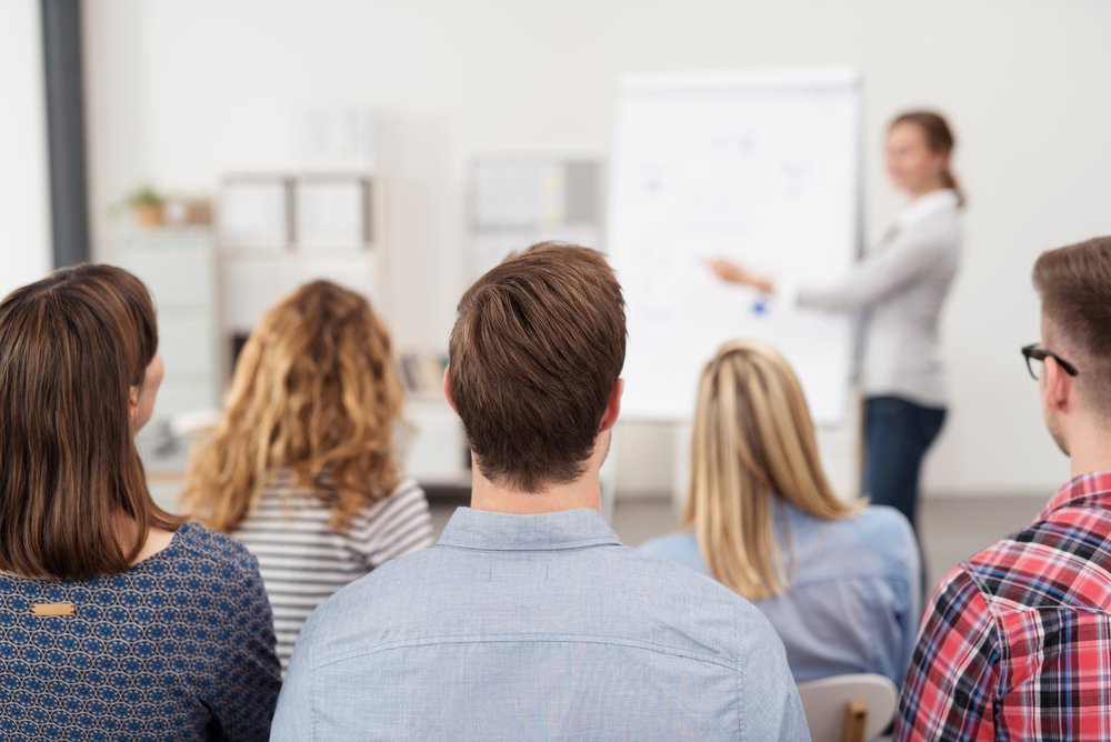 Rear View of Young Office Workers in Casual Outfits Listening to a Top Manager Explaining Something Using Illustrations.-2