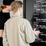 大型モニターのコードを確認しながらシステム開発を進めるエンジニア