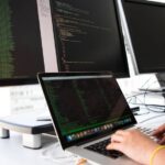 ノートパソコンでデータベース構築のコードを確認するエンジニアの手元