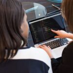 ノートパソコンのコードを確認しながら品質について話し合う開発チーム